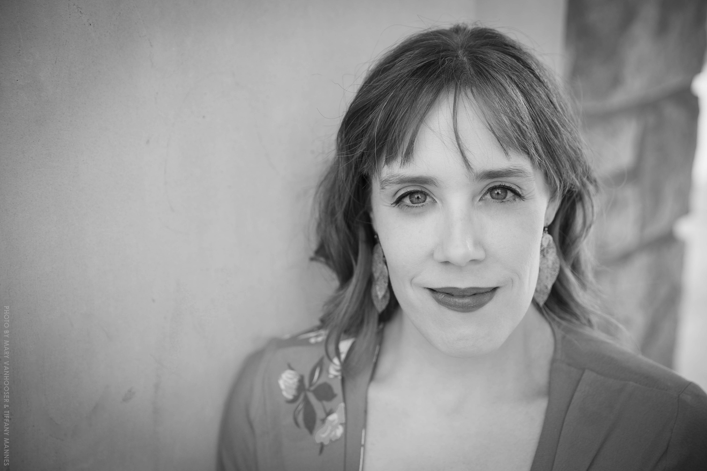 Black and white headshot of LV Wood looking toward the camera in front of a brick wall