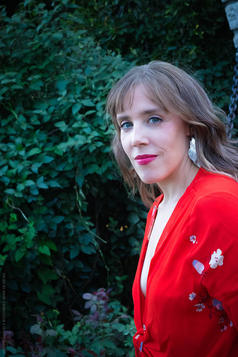 Color headshot of LV Wood looking away from the camera in front of a brick wall