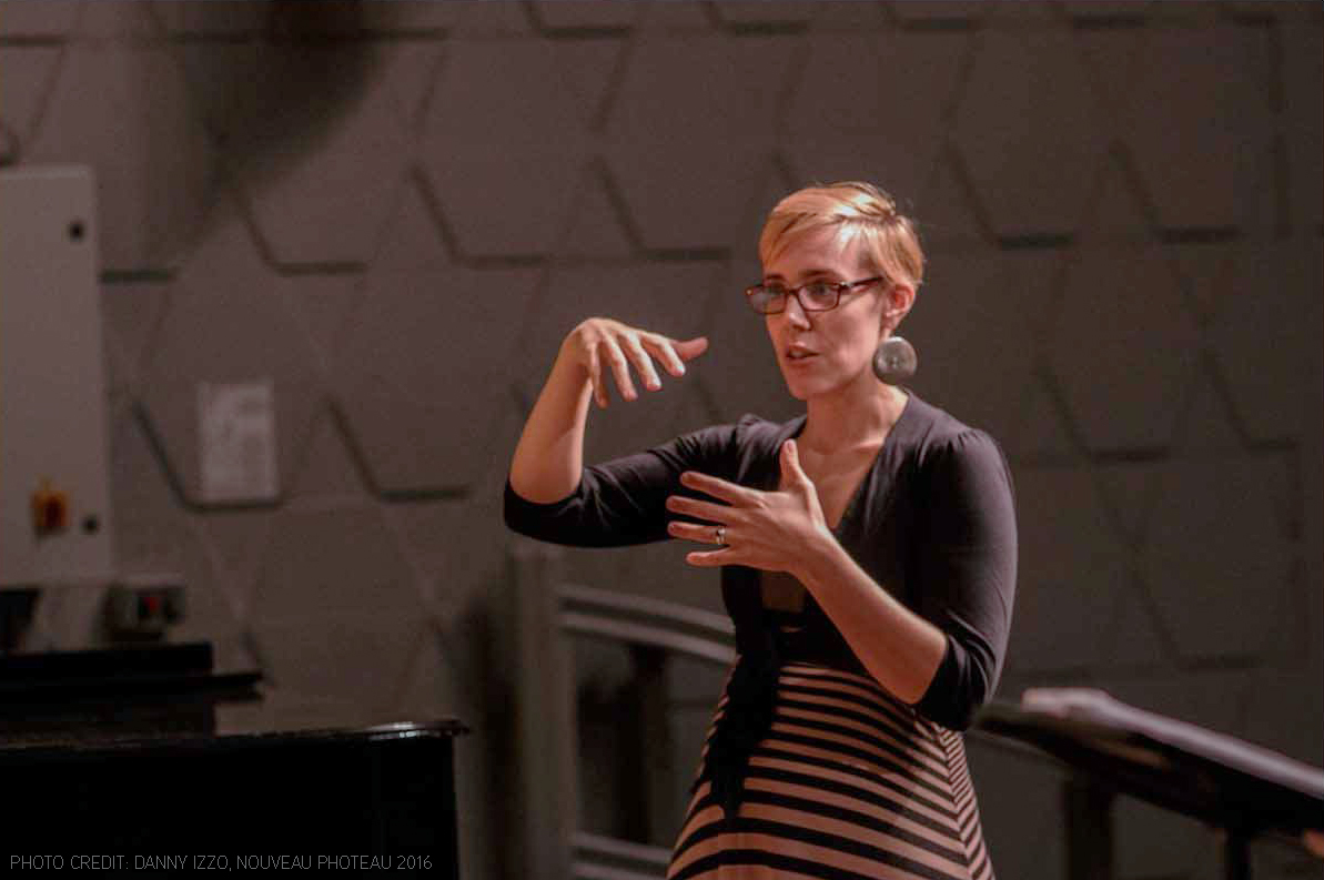 Headshot of Leslee Wood in a bright red blouse with a wry smile.